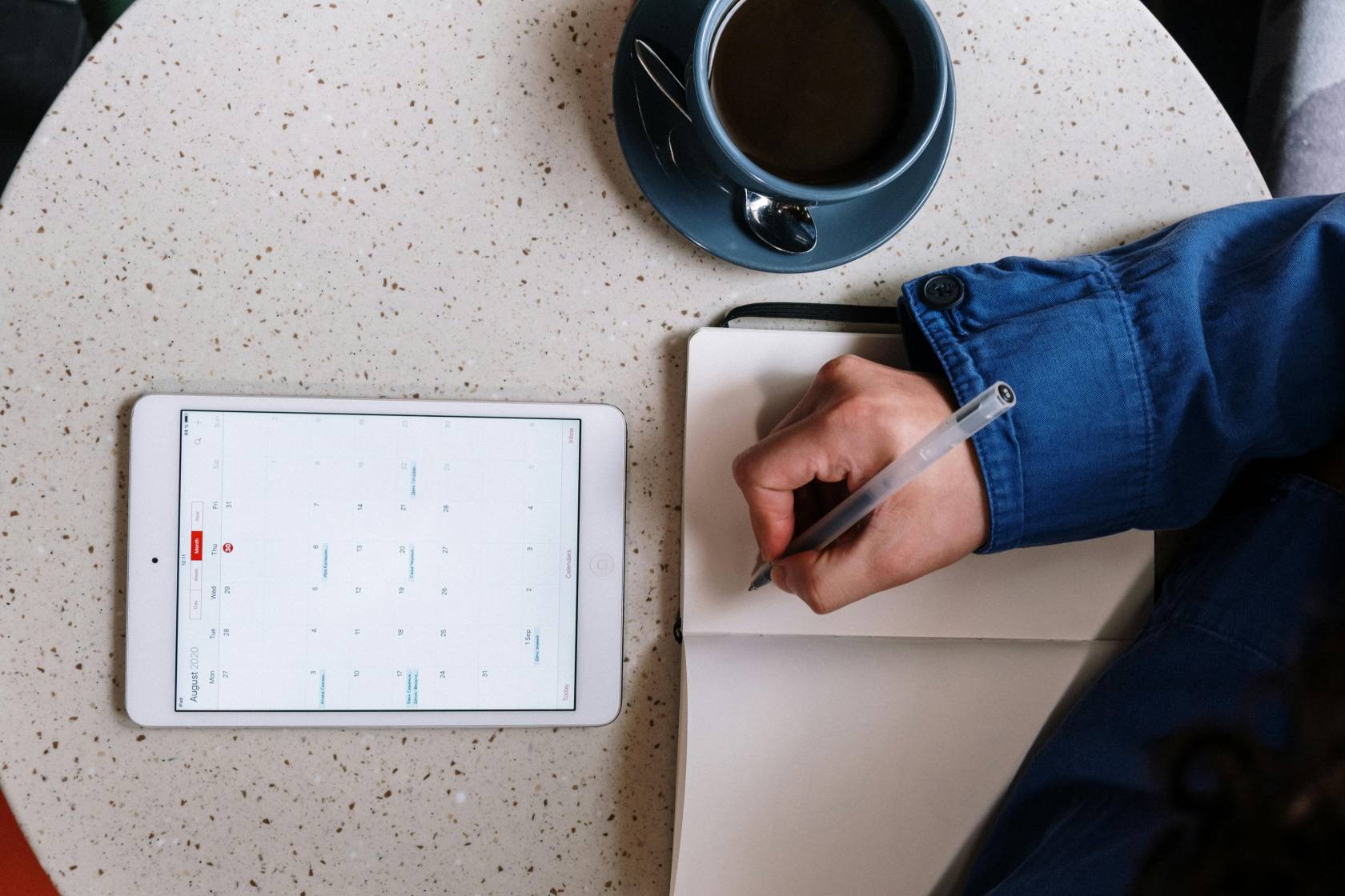 Electronic tablet with pen and teacup on saucer, surrounded by office supplies. Text reads "28 2 29 2 2 5 2"